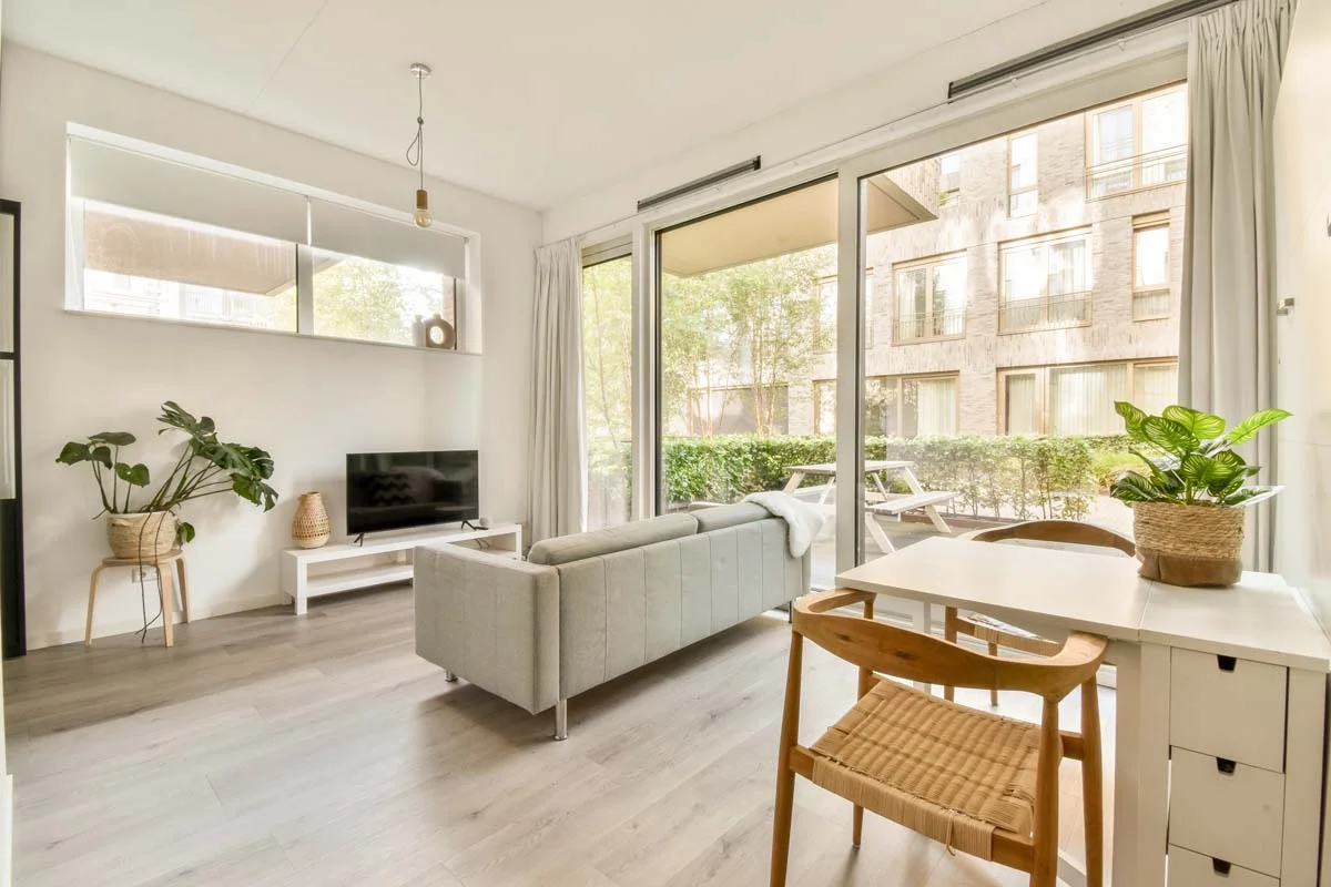 A modern and sunlit furnished apartment living room featuring stylish furniture and city views