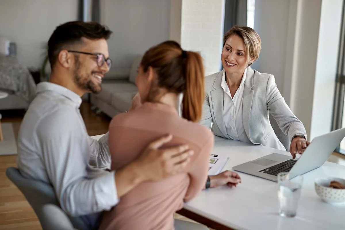 A professional property manager using laptop while talking with a couple during a meeting