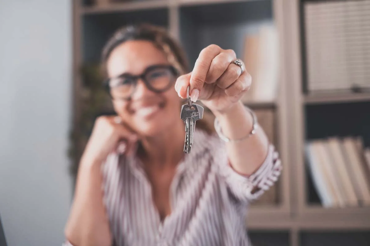 Close up shot of house keys in hand of smiling property owner, symbolizing a property management partnership