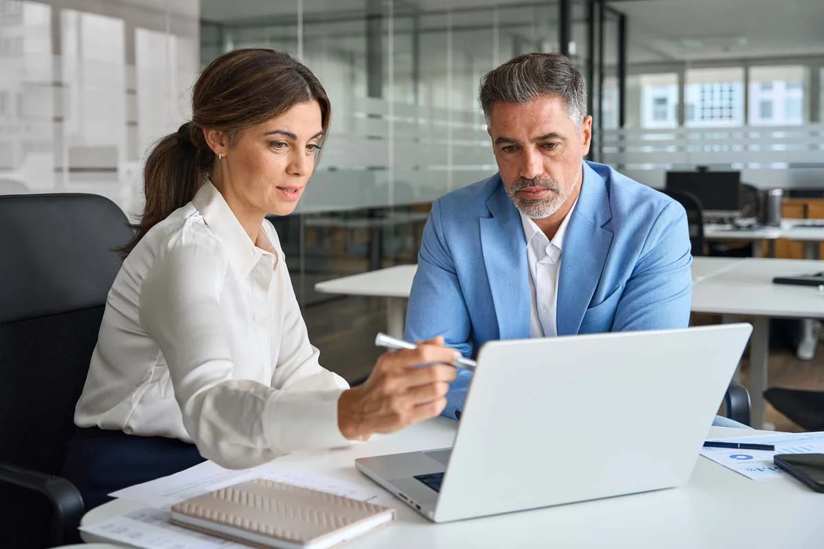 Real estate investors reviewing the performance of multiple rental properties on a computer