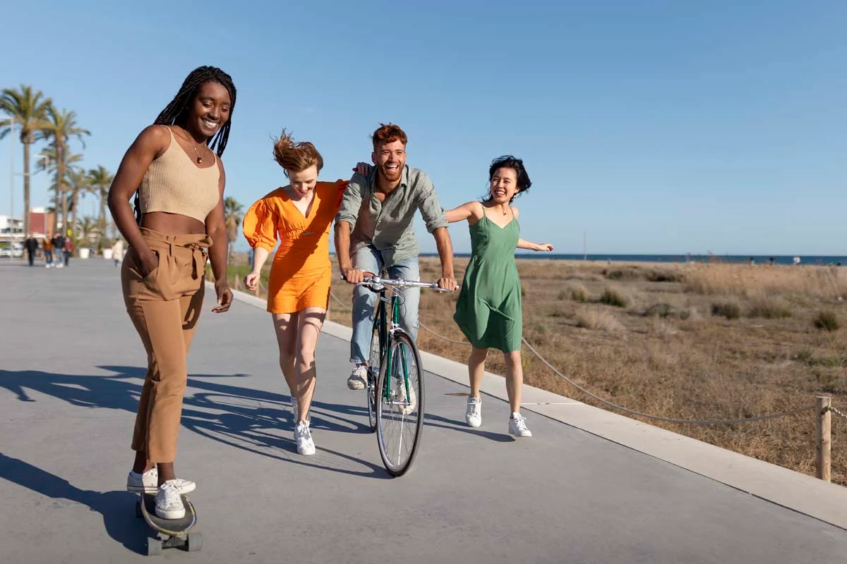 People enjoying a sunny day walking and riding bikes along the Venice Beach boardwalk