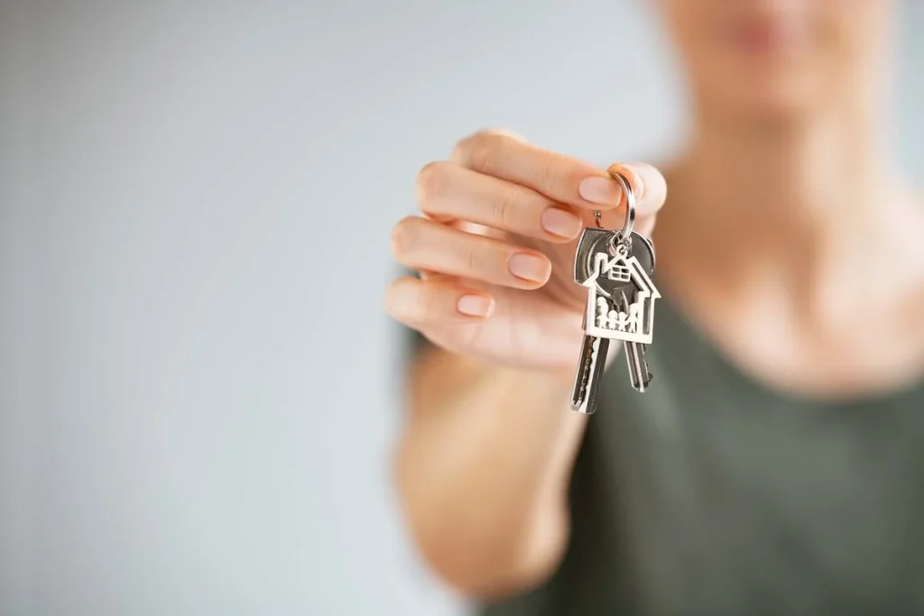 A close-up of a person holding house keys inside a bright, modern residential property