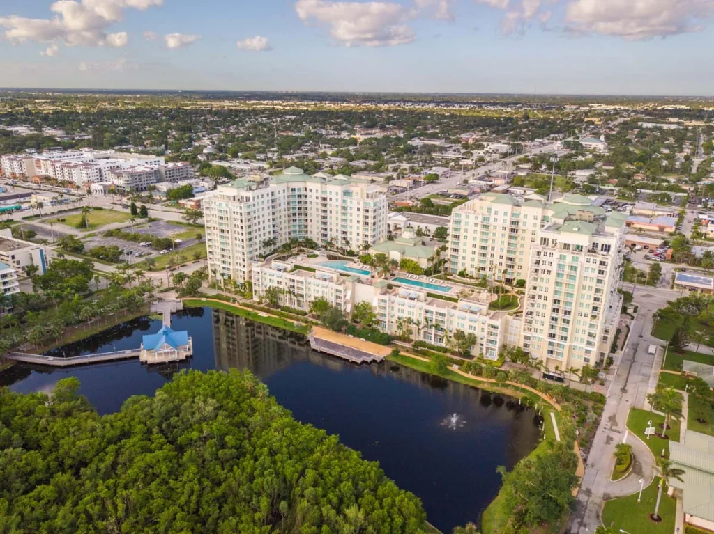 A sunny aerial view of a residential condominium in Boynton Beach Florida featuring tropical landscaping