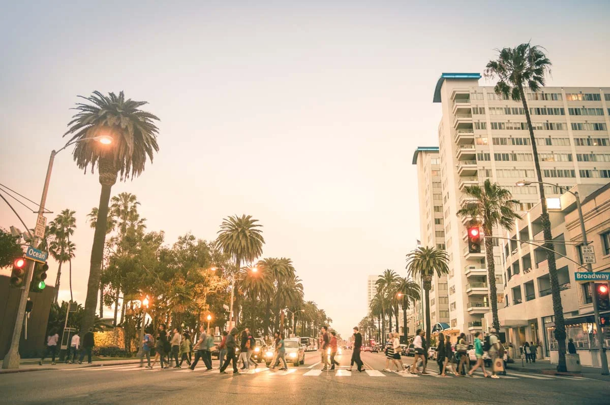 Locals and tourists walking on zebra crossing on Ocean Ave in Santa Monica after sunset