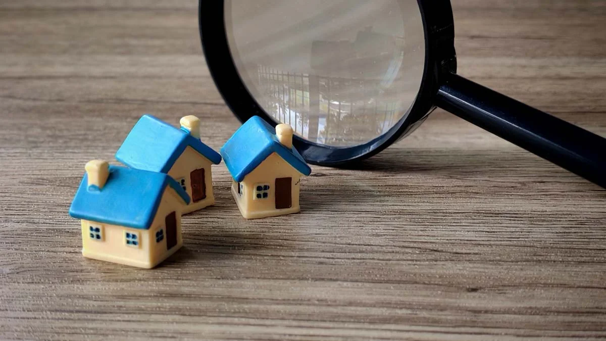 Miniature houses and magnifying glass symbolizing location analysis and assessment