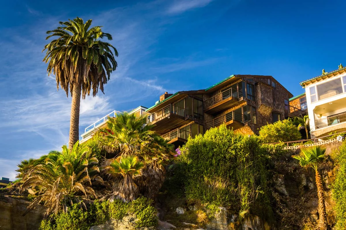 A luxury modern beach house with palm trees under a blue sky in Orange County, California
