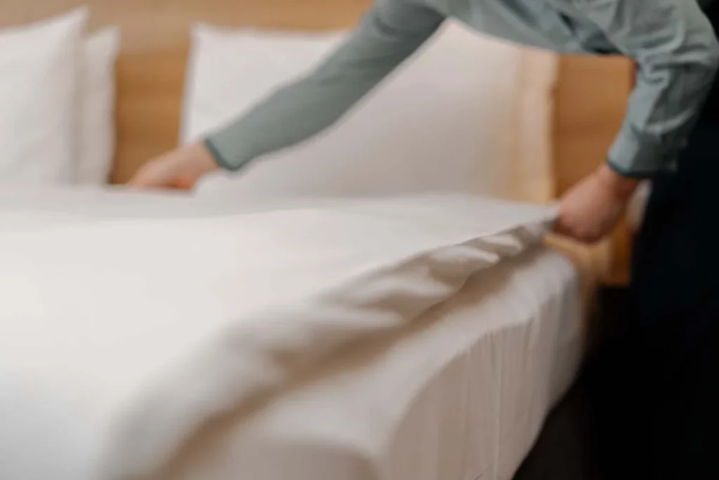 A professional housekeeper preparing a luxury guest room for a short-term rental stay