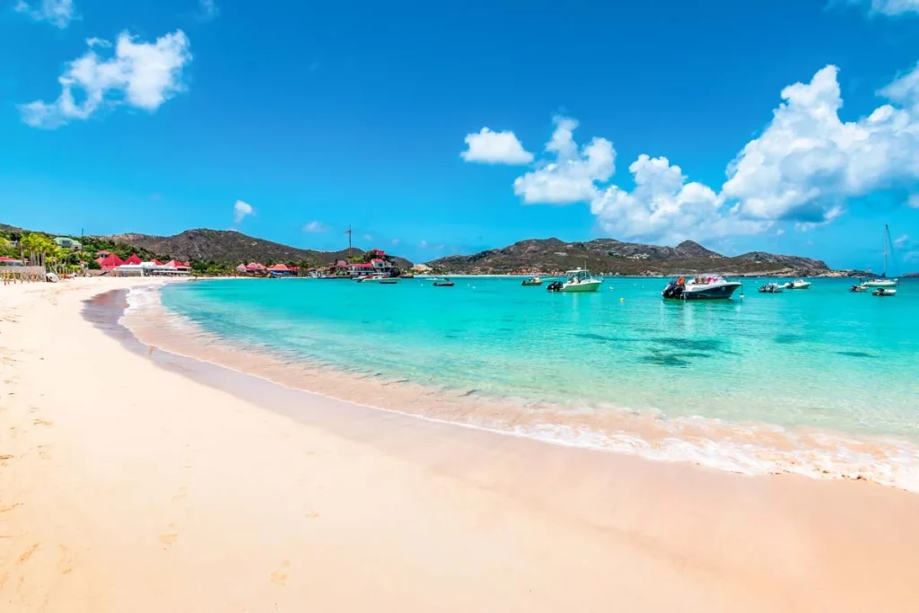 A quiet white sand beach in St. Barts with turquoise water and tropical greenery