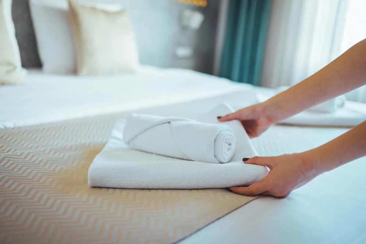 Close up of high end hotel style bedding and fresh towels in a vacation rental