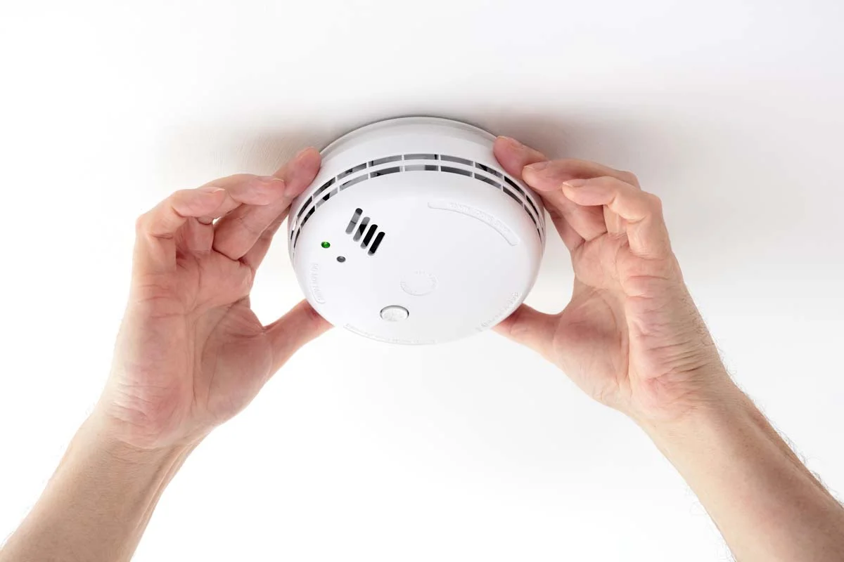 Performing a safety check on a smoke detector as part of the mandatory RRIO inspection checklist