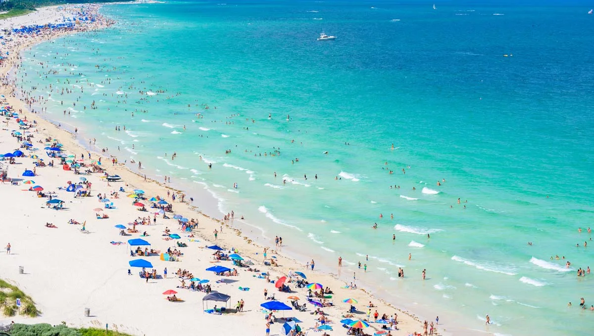 Sunny day on South Beach Miami featuring white sand, turquoise water, and a colorful lifeguard stand
