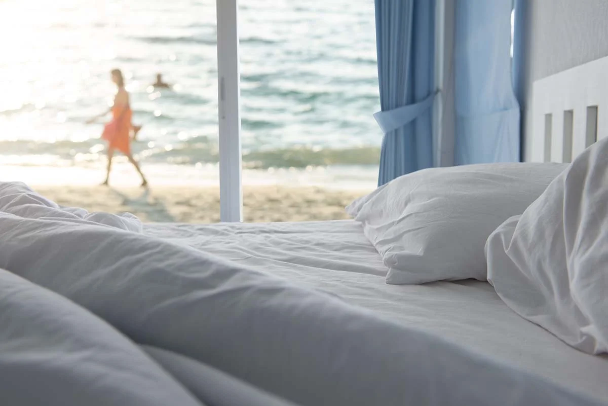 White pillows and bedding sheet in clean bedroom by the beach