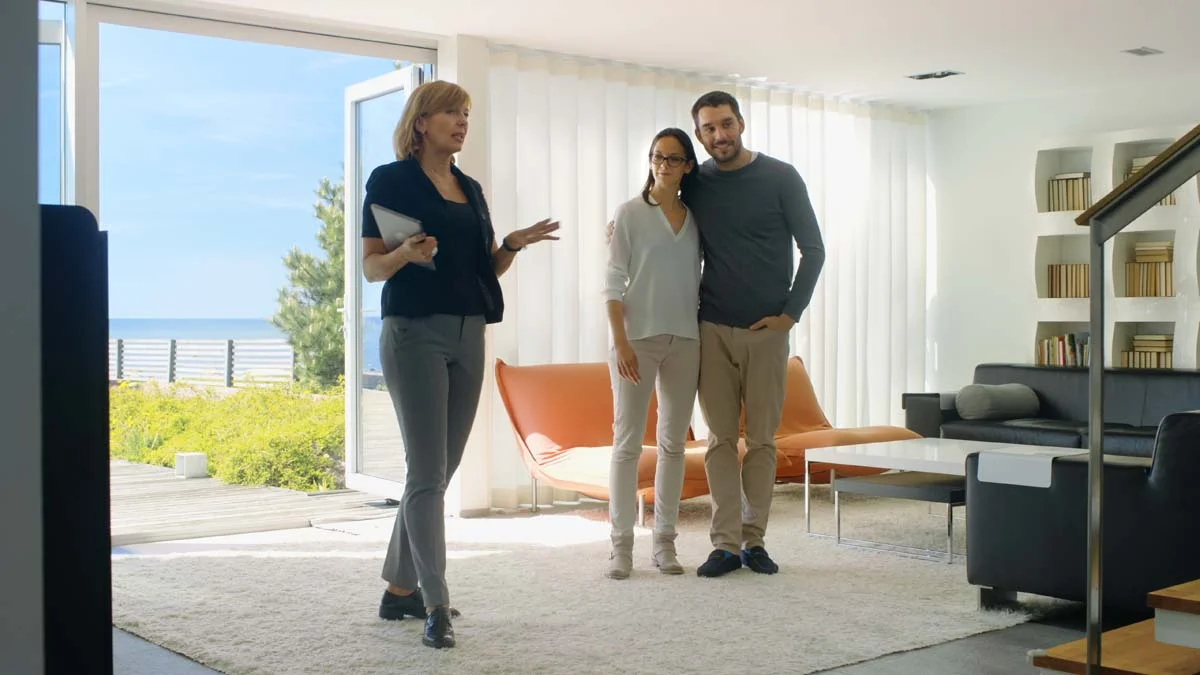 A professional property manager showing clients around a clean interior of a luxury vacation rental in Orange County