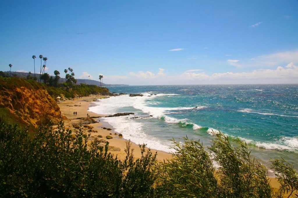 A sunny coastline in Orange County, California with blue ocean waves and golden sand