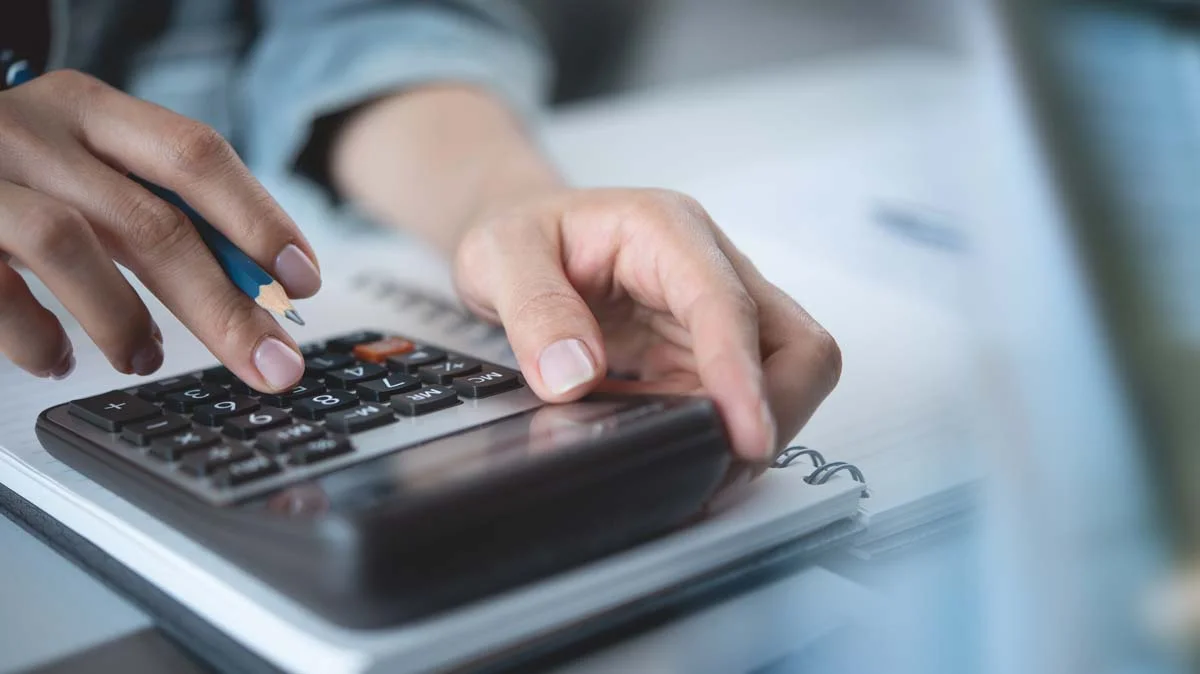 Close up of a hand using a calculator symbolizing Seattle short term rental RRIO safety standards and costs