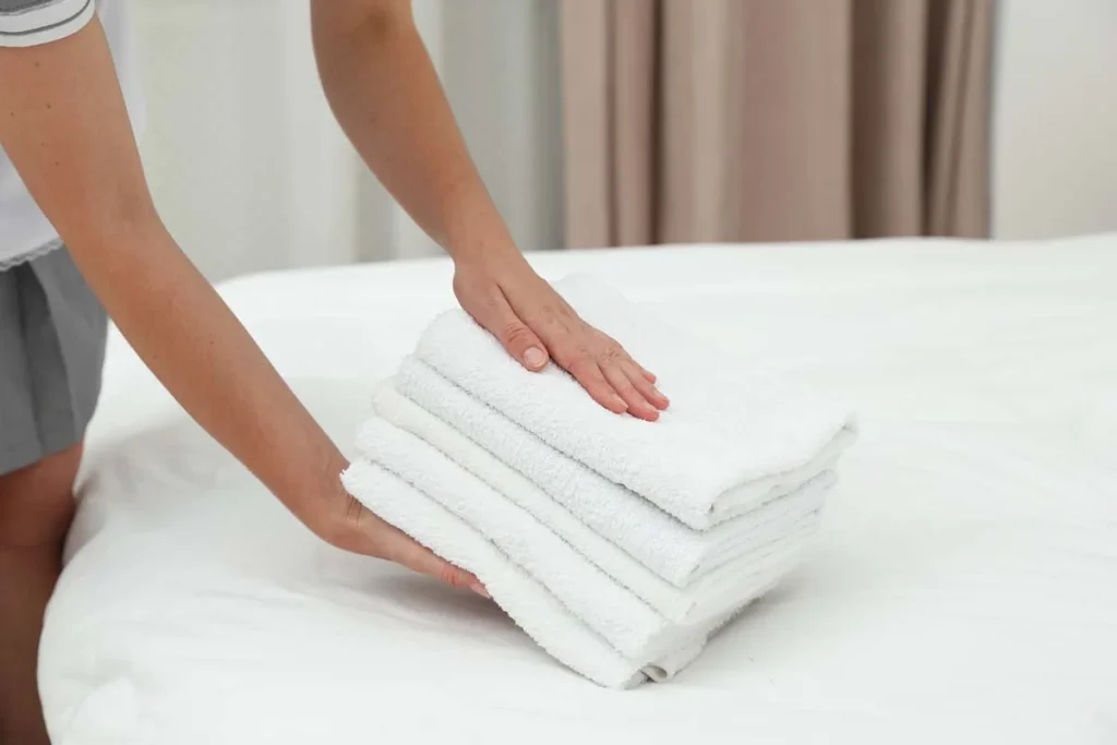 Fresh white towels folded on a clean bed in a luxury vacation rental.