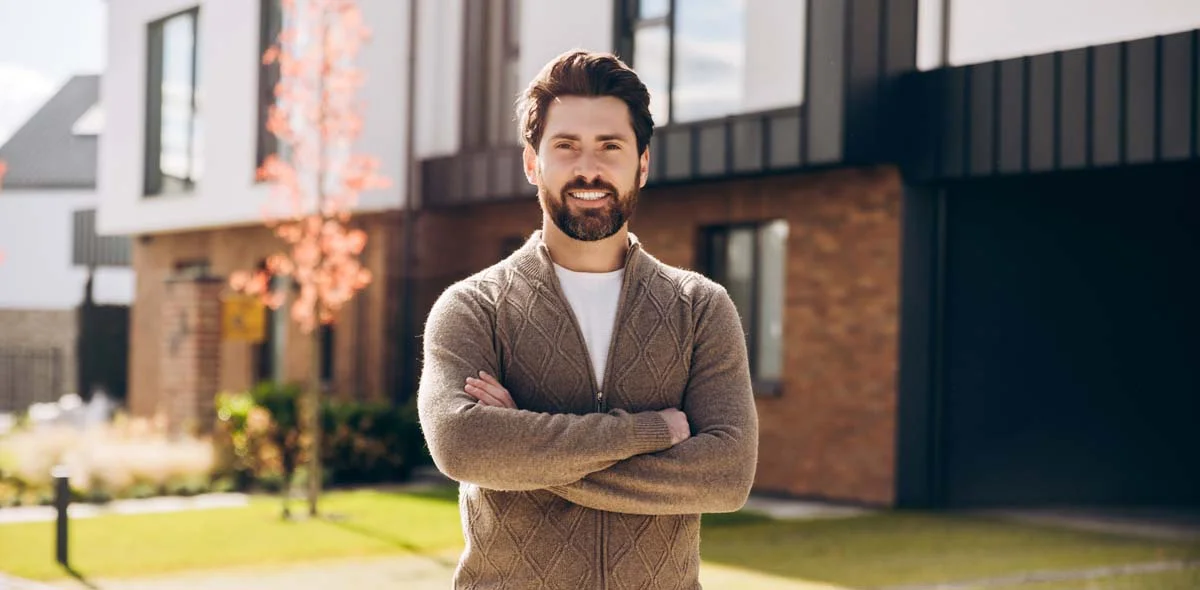 Happy homeowner standing in front of their beautiful residential property