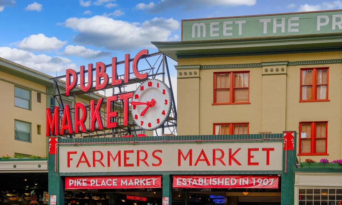 The famous red neon sign at Pike Place Market with local vendors and tourists