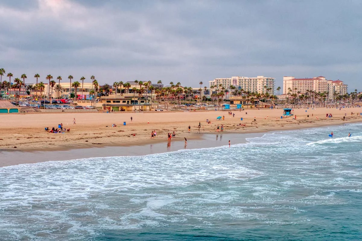Wide view of Huntington Beach, with beach houses in the background that are suitable for short term rentals