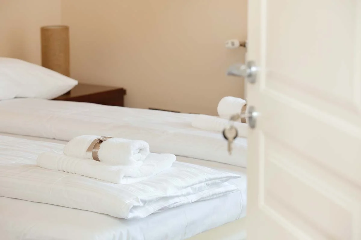 A clean, brightly lit bedroom with freshly folded towels ready for arriving guests