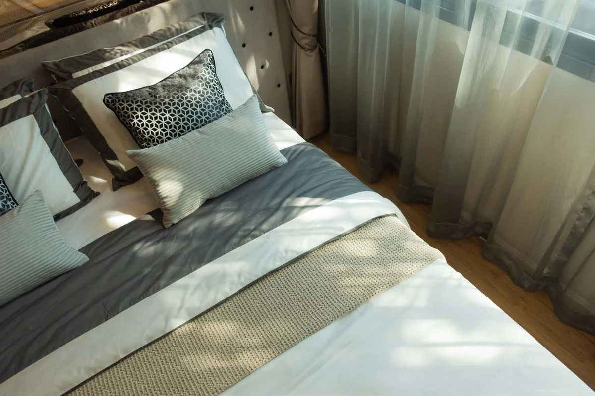 A neatly made bed with fresh linens in a bright guest bedroom