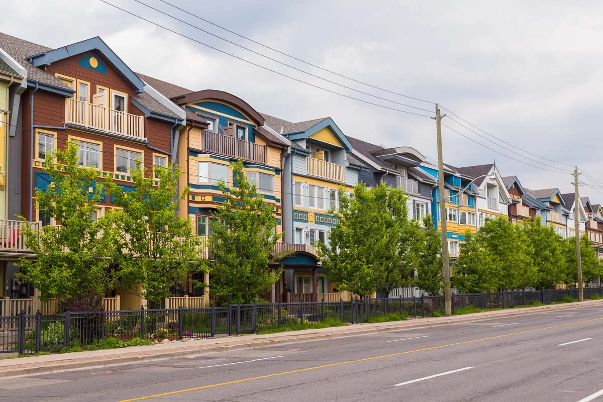 A peaceful, tree-lined residential street in a Toronto neighborhood with low-rise homes
