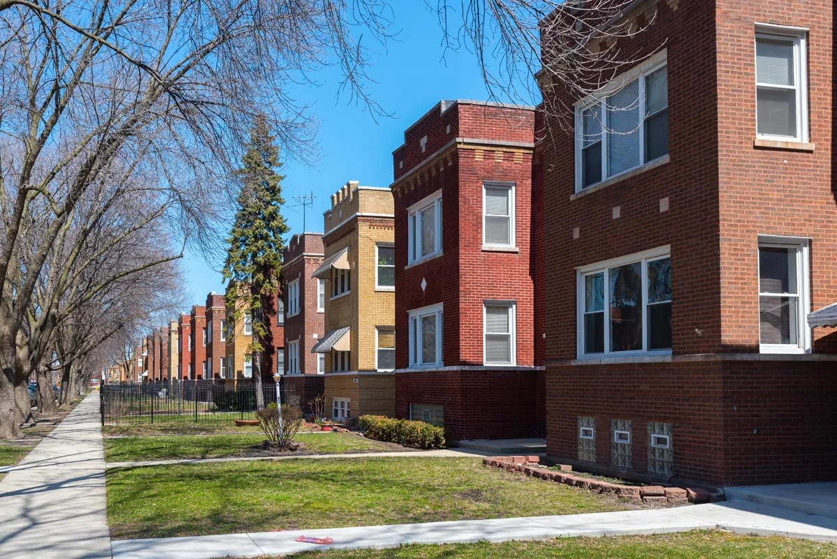 A peaceful tree-lined street with historic brick homes in a residential Chicago neighborhood