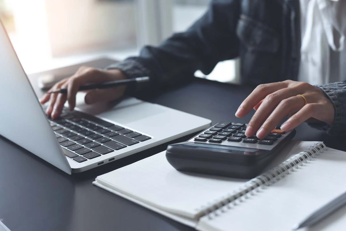 A person calculating lodging taxes on a laptop computer at a desk