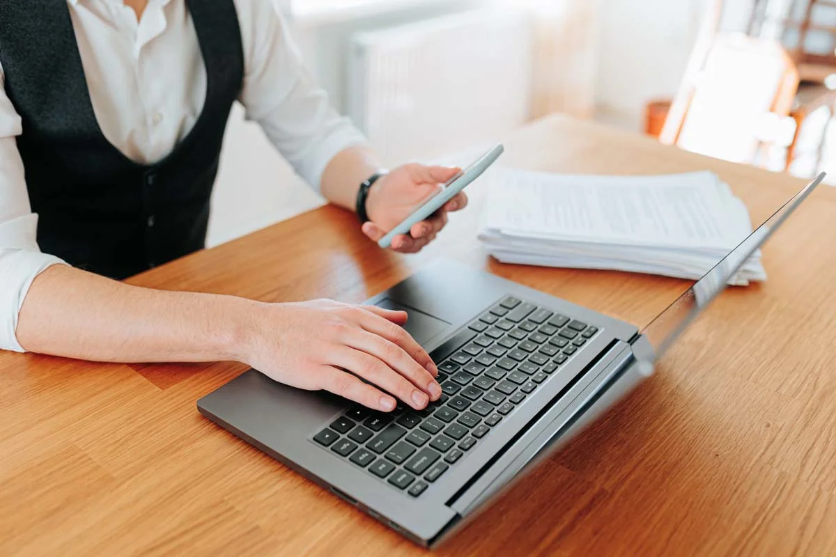 A person using a laptop on a clean desk to manage online business registration records