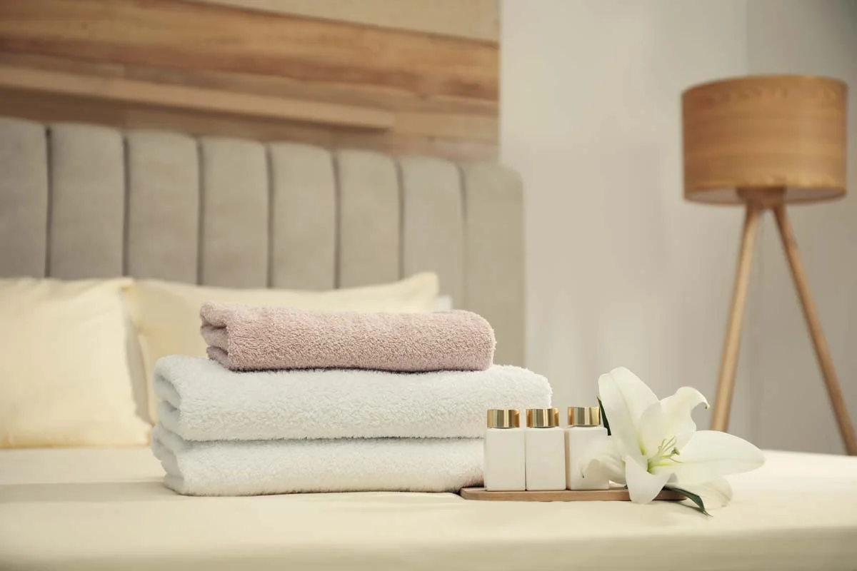 Freshly folded luxury white towels on a neatly made bed in a professionally managed rental apartment