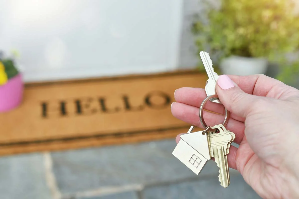 Housekeys on the front porch with a “Hello” doormat
