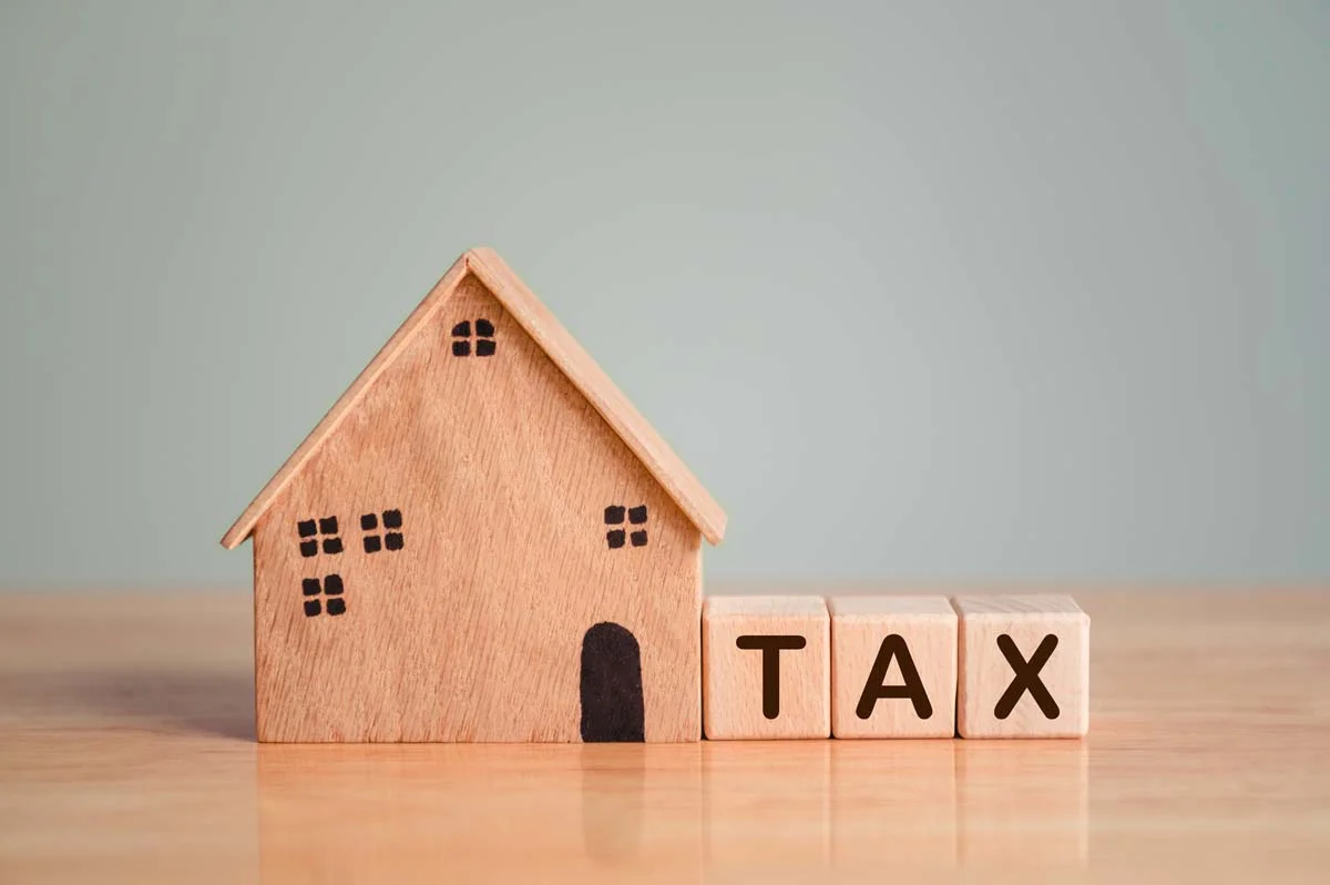 Miniature house and wooden blocks with TAX carved on it, representing Kirkland tax rate 2026