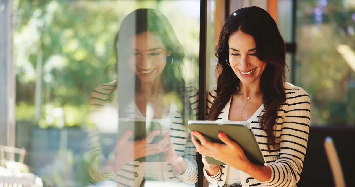Professional vacation rental manager smiling while holding a digital tablet in a bright home