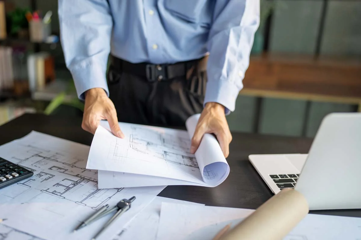 Property owner reviewing floor plans and application documents on a desk