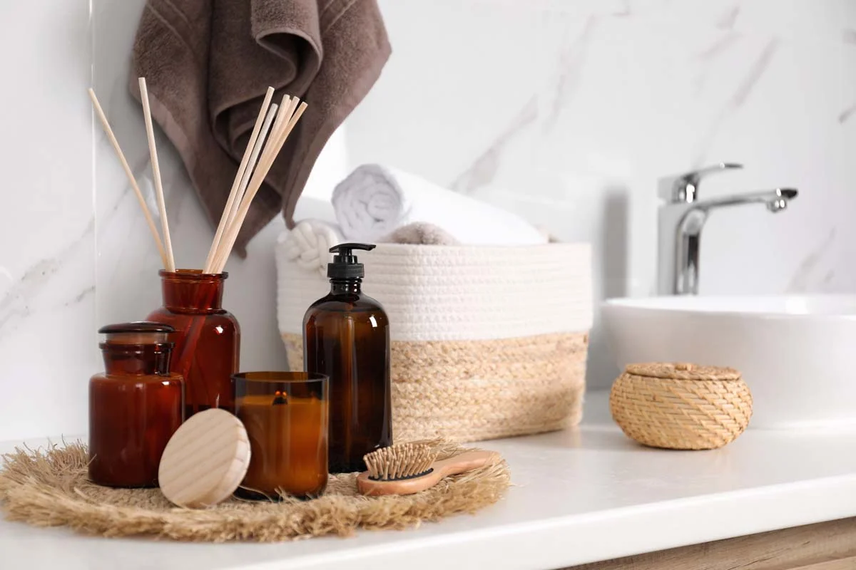 Refillable glass soap and shampoo dispensers on a clean bathroom countertop to reduce plastic waste