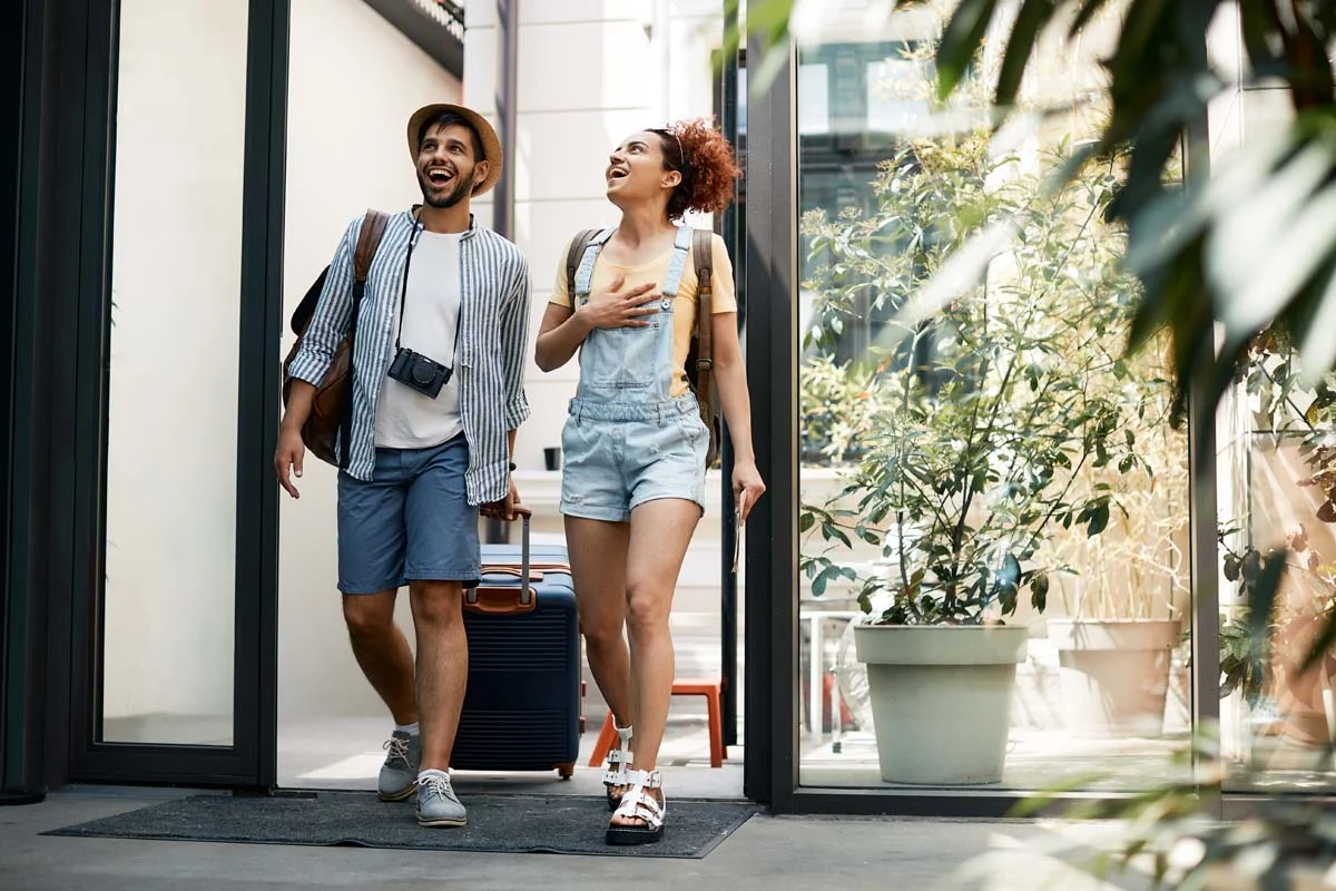 Travelers arriving at a cozy short term rental property with a suitcas