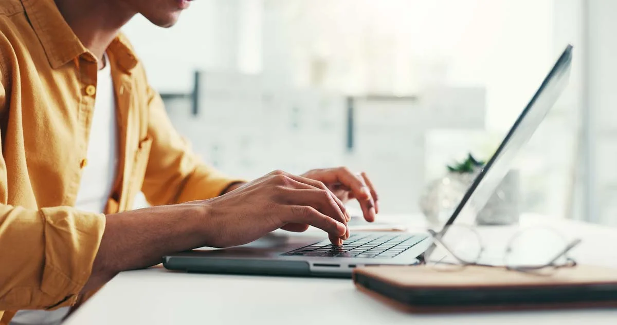 Vacation rental host typing on a laptop to communicate with an inquiring traveler