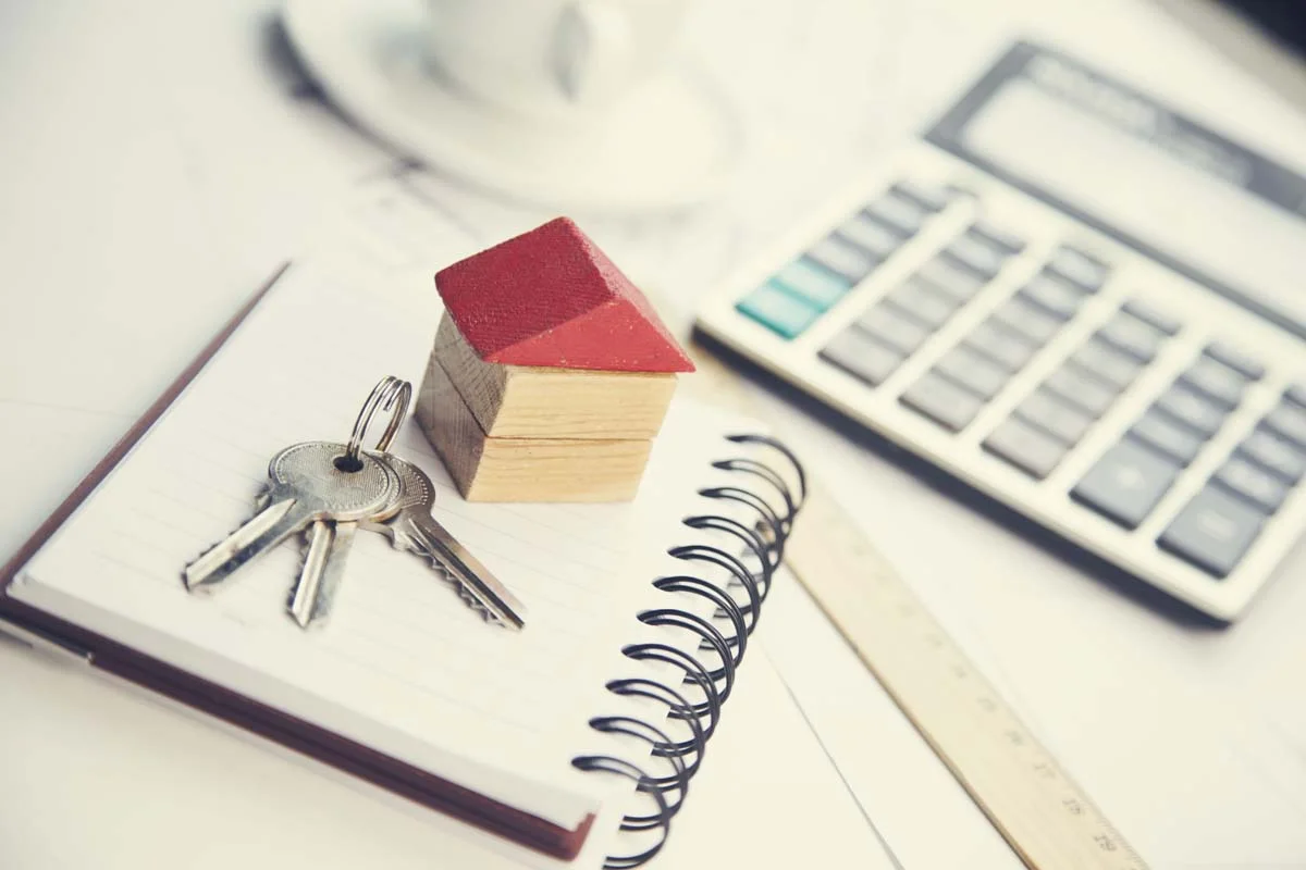 A calculator, house keys, and a notepad representing vacation rental financial planning and ROI calculations