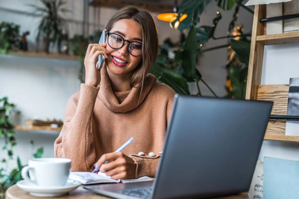 Property owner using a smartphone while working on a laptop