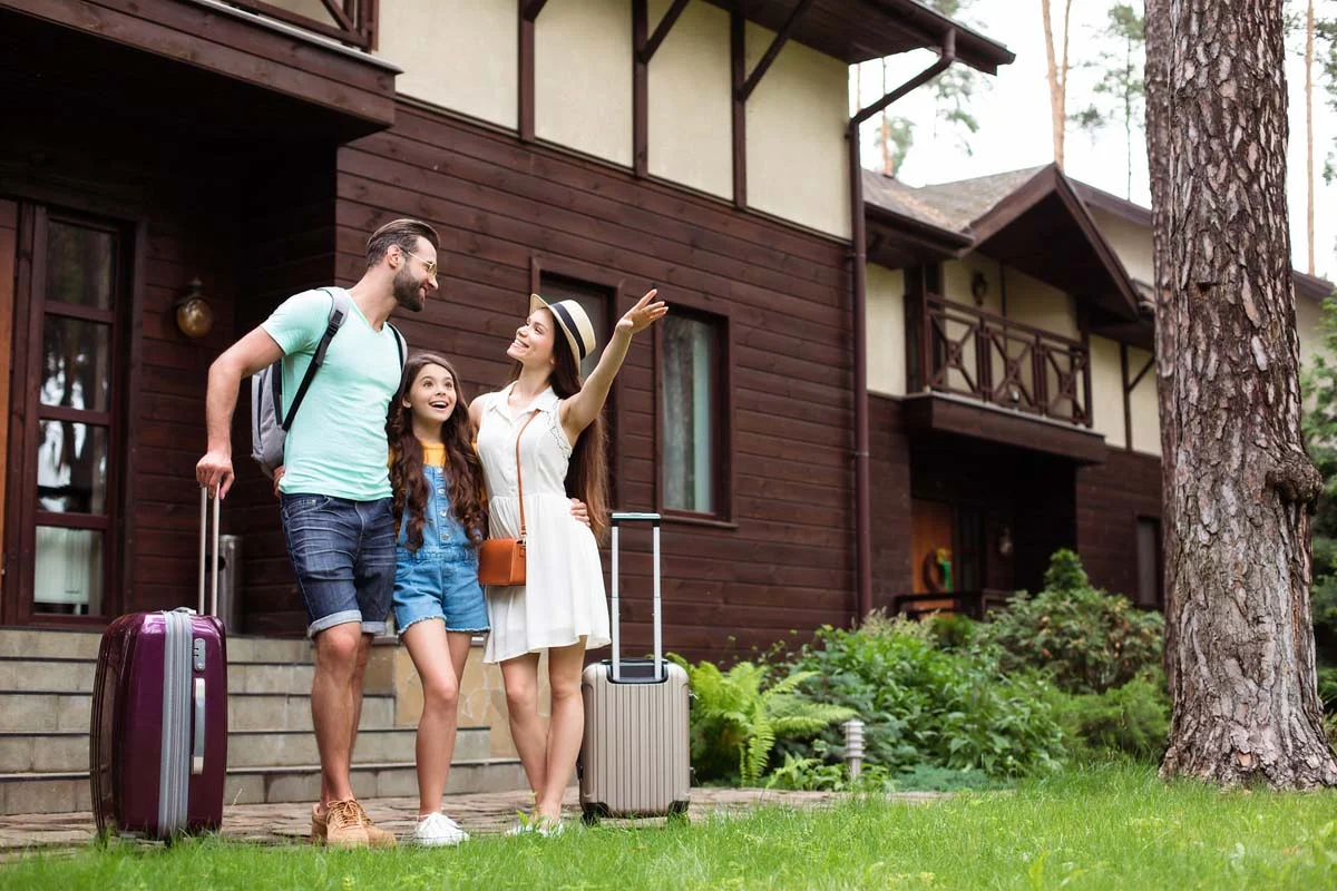 A family arriving at a private vacation rental home with their luggage