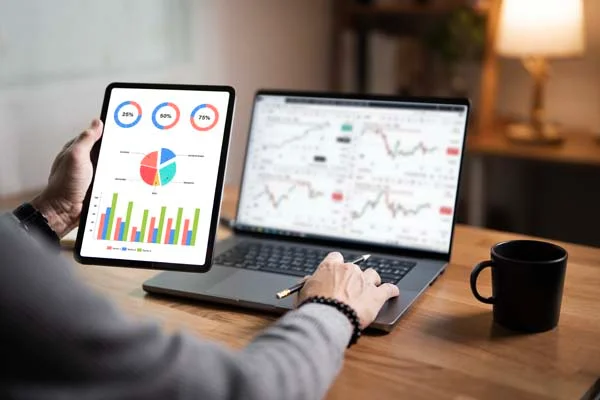 A modern digital tablet and laptop showing upward financial charts and occupancy metrics for rental income optimization