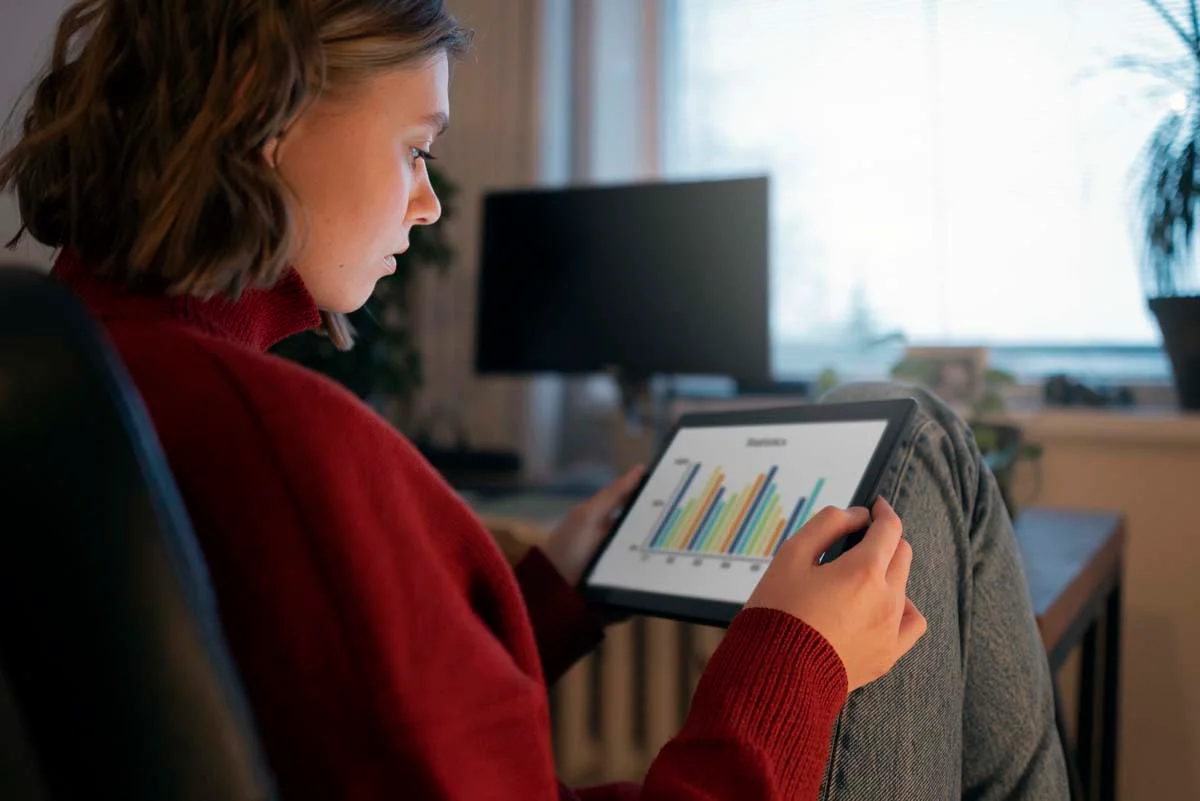 Close-up of a property owner using a tablet to view a digital dashboard showing short-term rental booking analytics and monthly performance charts