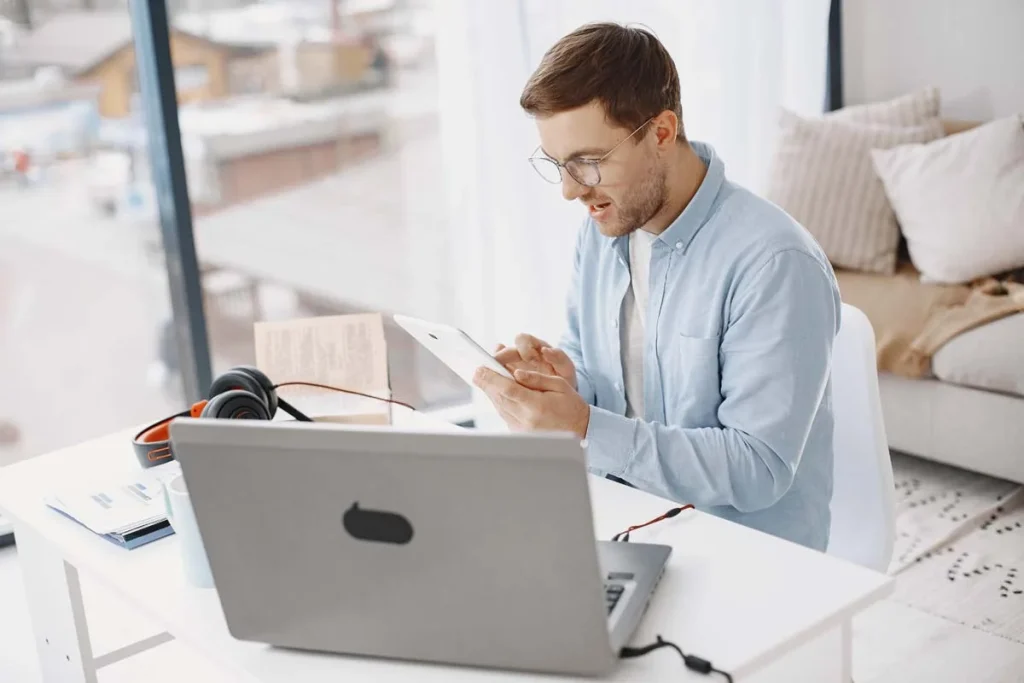 A professional property host reviewing short-term rental booking platforms on a laptop inside a modern home