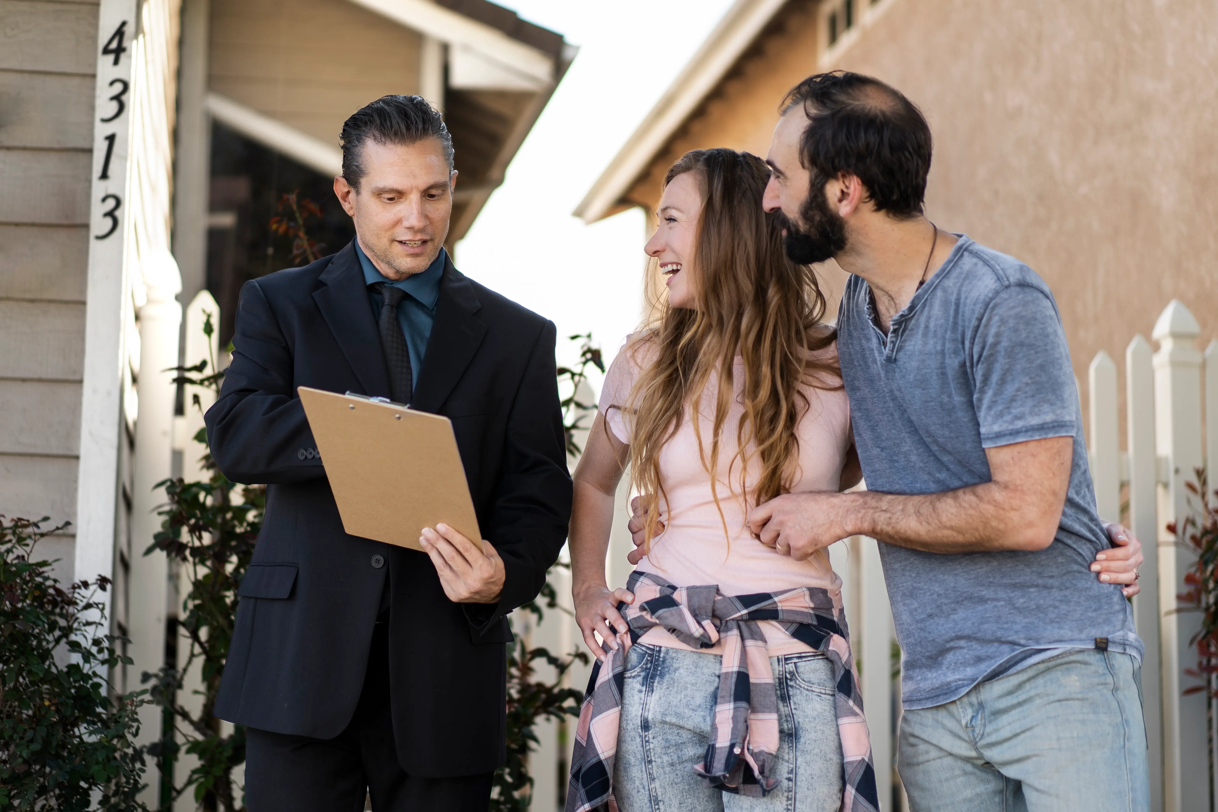 An onboarding manager showing a welcome folder and tablet to a homeowner during their first property walkthrough