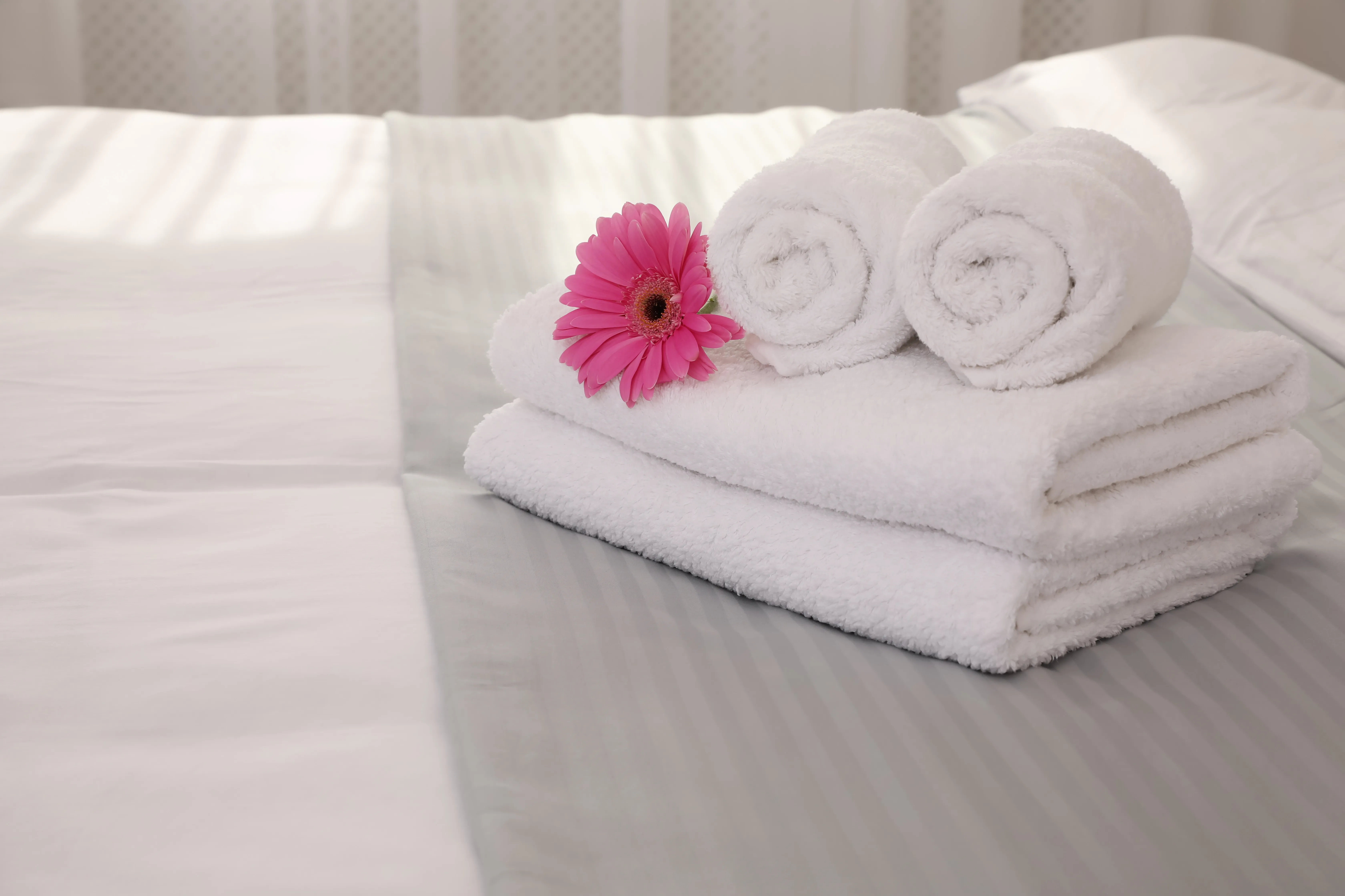 Fresh white towels folded neatly on a bed in a professionally managed rental property.