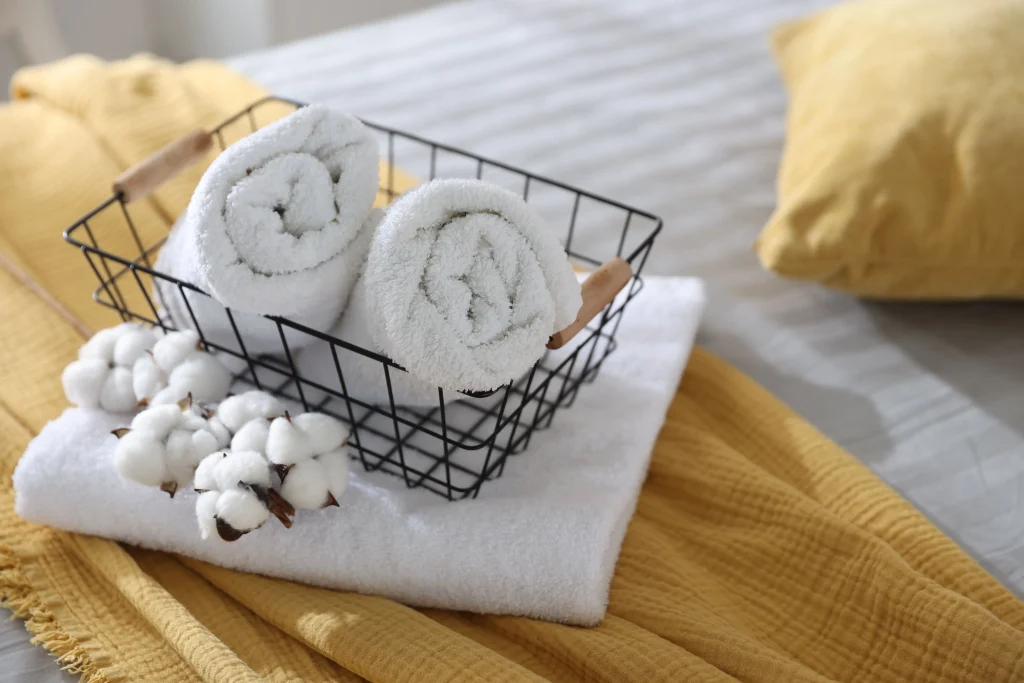 Freshly folded white towels on a neatly made bed in a professionally managed short-term rental