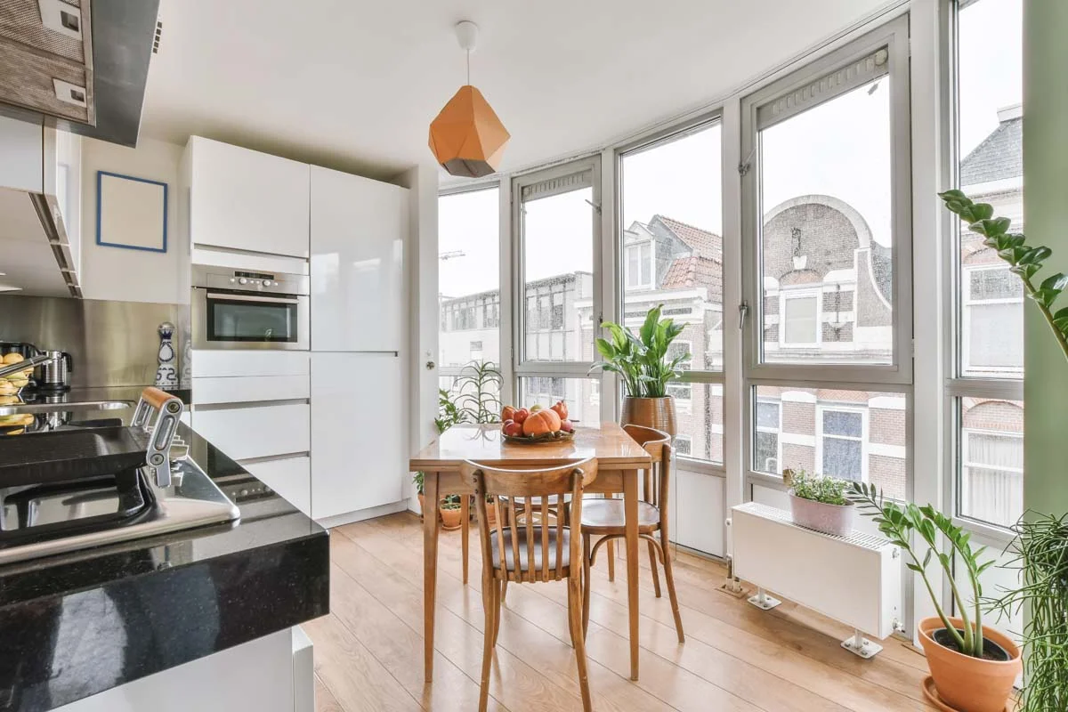 Modern condo living room and kitchen with sofa, marble coffee table, stainless steel appliances, and floor-to-ceiling windows overlooking city skyline
