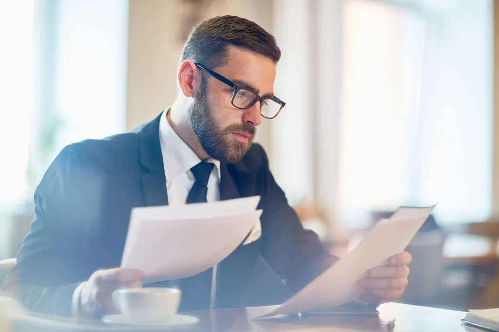 A professional businessman reviewing official paperwork at a workspace desk.