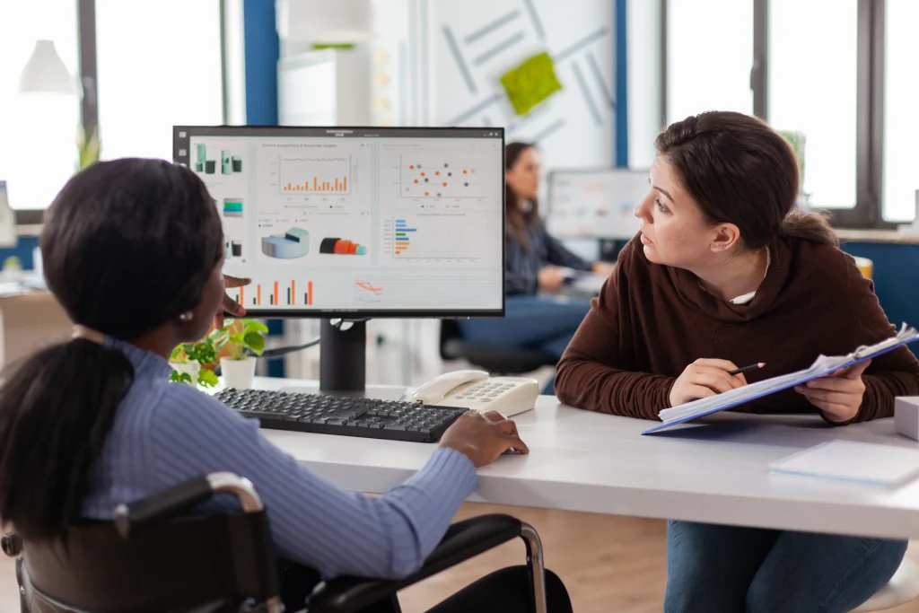 An advisor guiding a client through data and charts on a laptop.