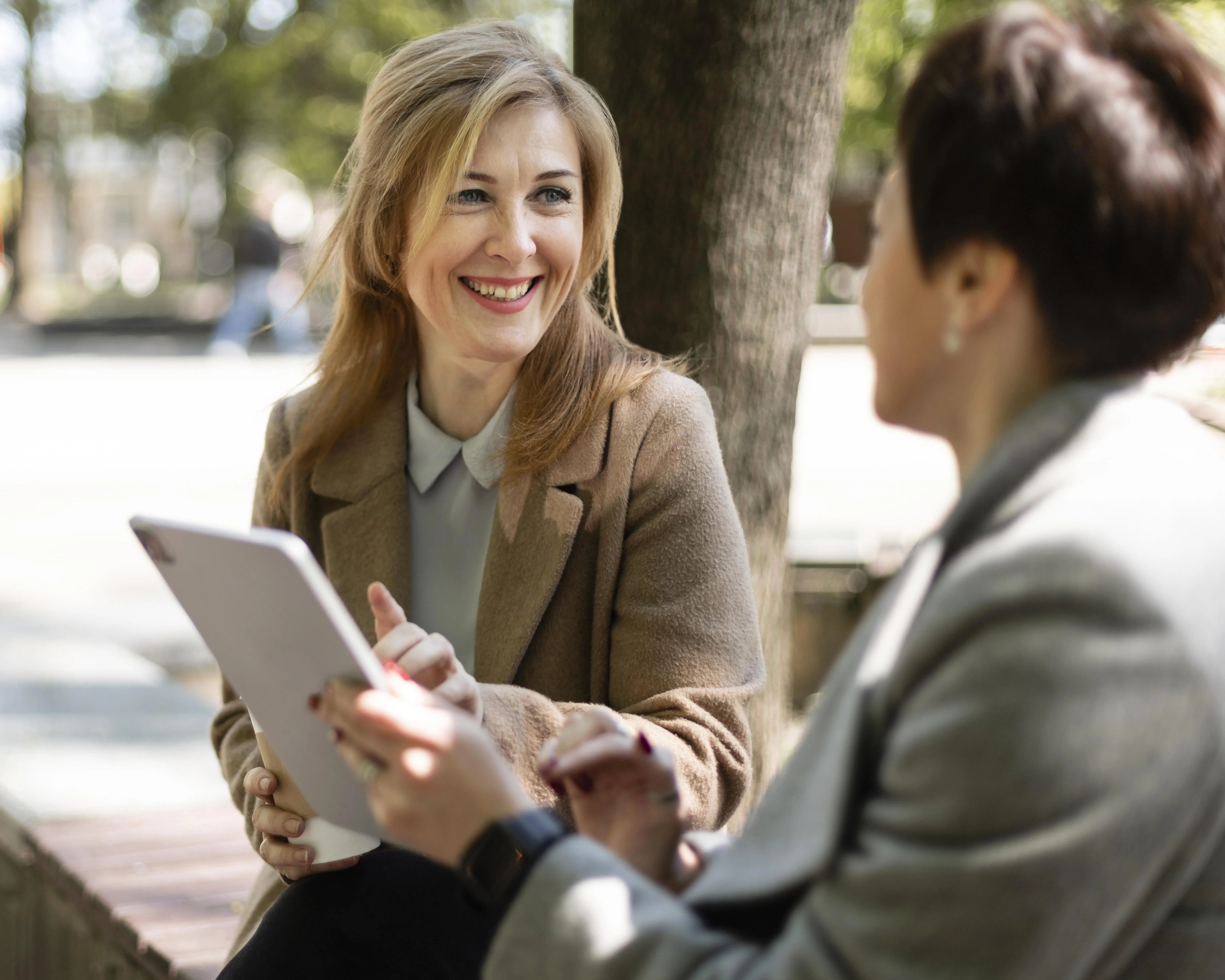 An agent using a tablet to explain information to a client outdoors.